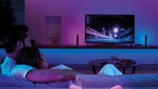 Philips Hue Play Sync system in use, with lights shining on a wall matching a video game image on a TV screen