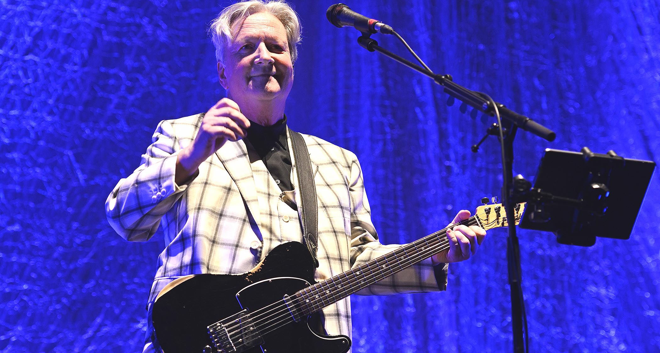 Glenn Tilbrook performs in a light checked suit with a black Telecaster