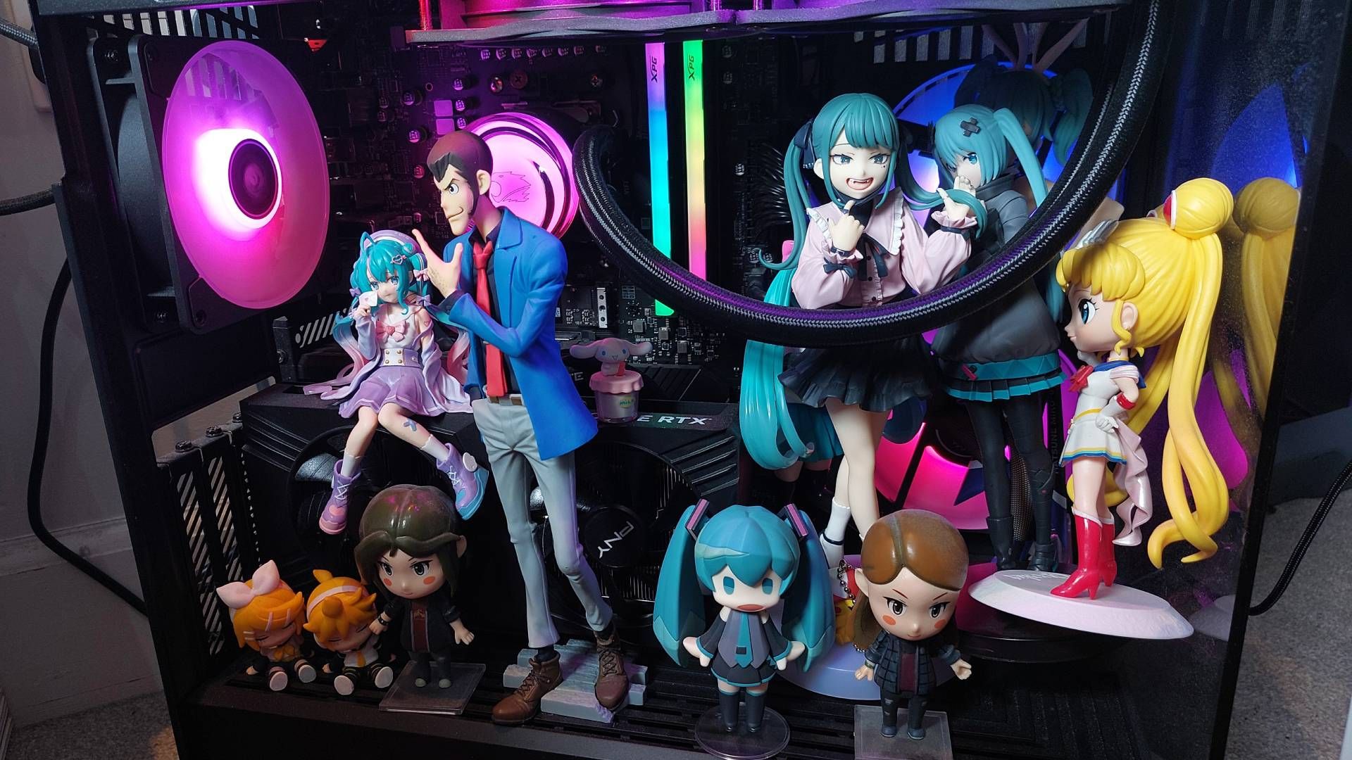 A PC with many anime figures placed inside. It looks quite crowded and impractical. The RGB lighting really makes it pop though.