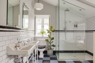 school style bathroom with blue and black checked tiles, white sinks and shower cubicle