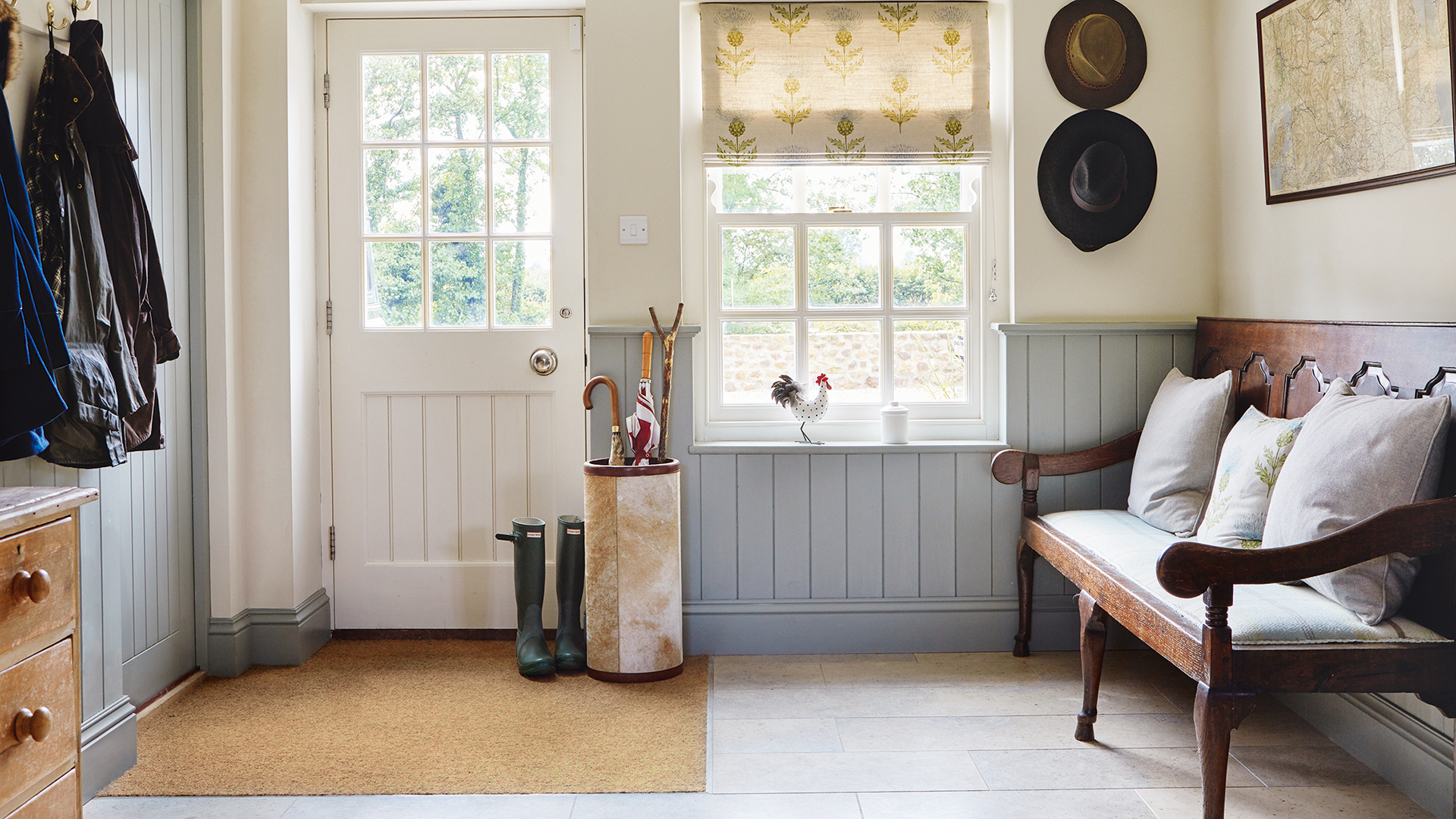 Country house hallway with pale blue wall panelling built-in doormat and wooden bench with cushions