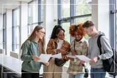 Smiling students in corridor comparing exam results