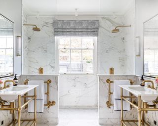 White shared bathroom with white marble walls and brass details