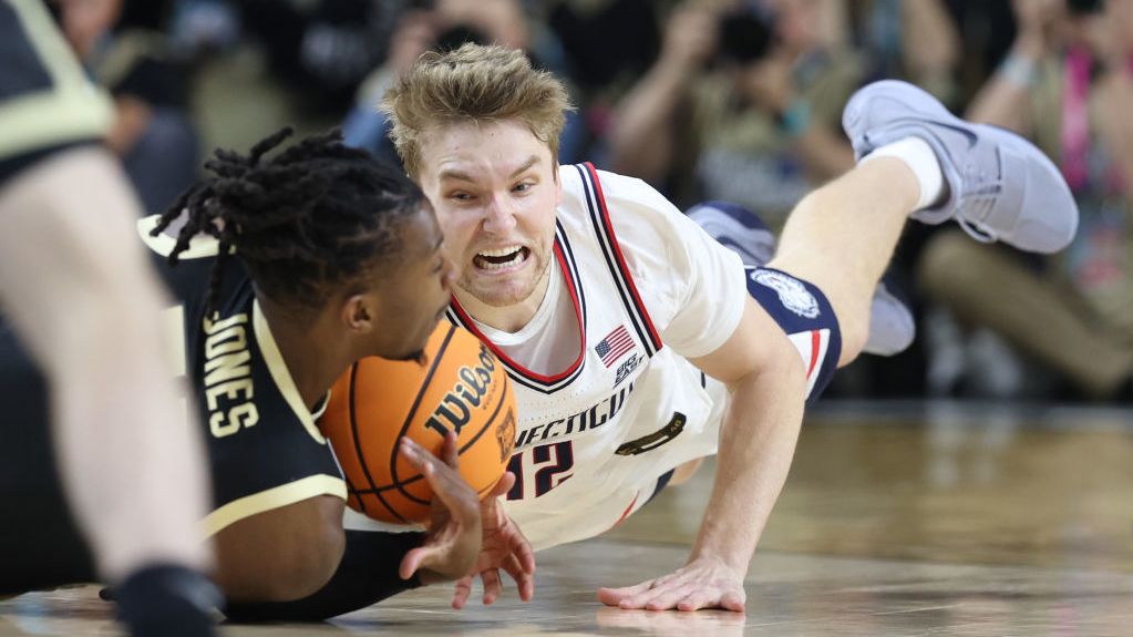 Lance Jones No.55 of the Purdue Boilermakers and Cam Spencer No.12 of the Connecticut Huskies dive after a loose ball the NCAA Men&#039;s Basketball Tournament in April 2024