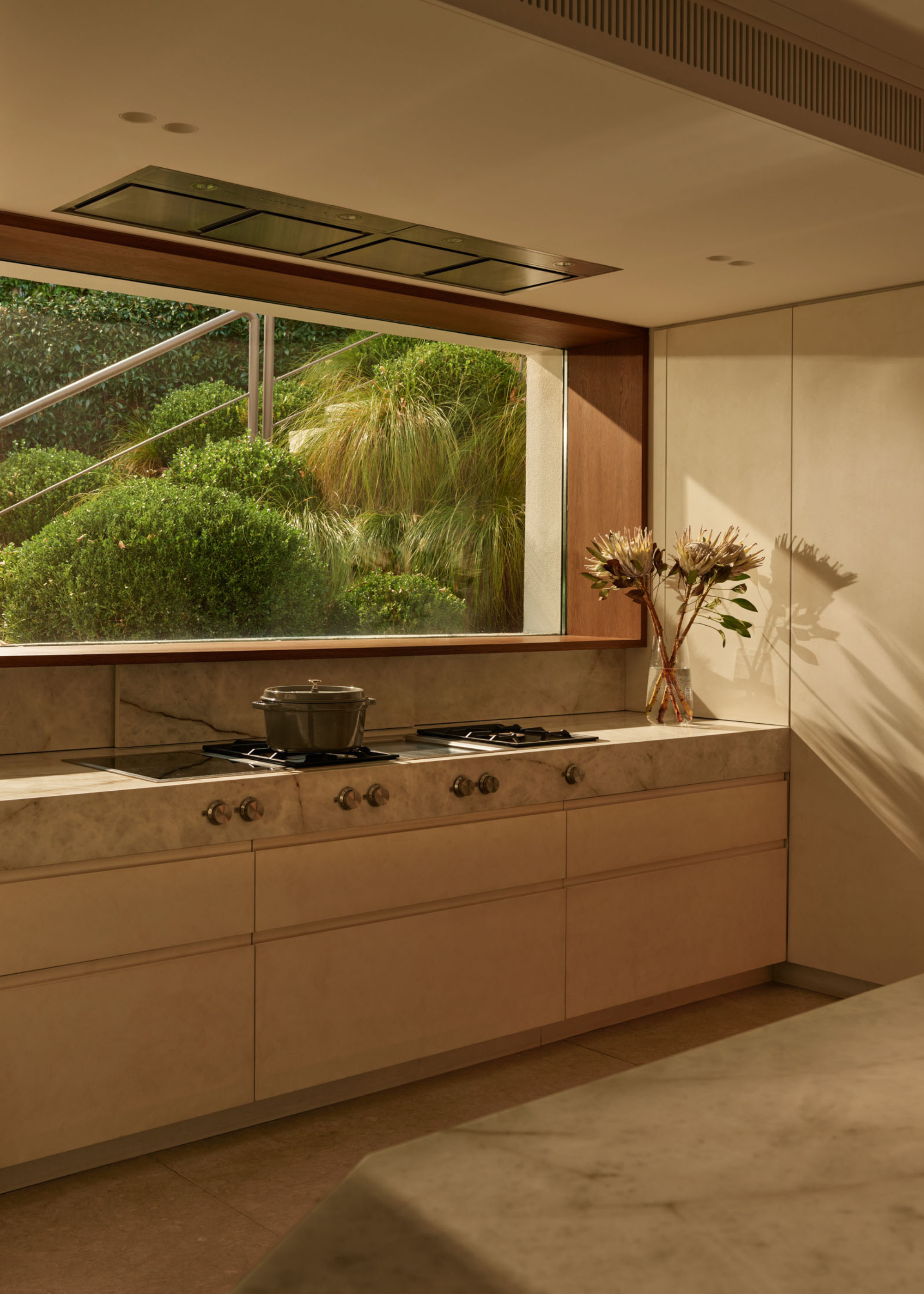 A bright kitchen with a gallery window a marble stovetop and beige drawers