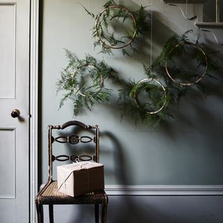 room with grey wall and wooden chair with plants on wall.