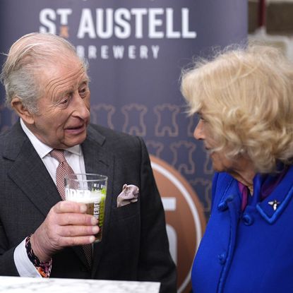 King Charles holding a beer talking to Queen Camilla 