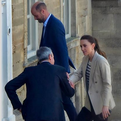 Princess Kate shaking hands with a man with Prince William walking behind her