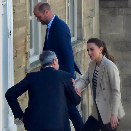 Princess Kate shaking hands with a man with Prince William walking behind her