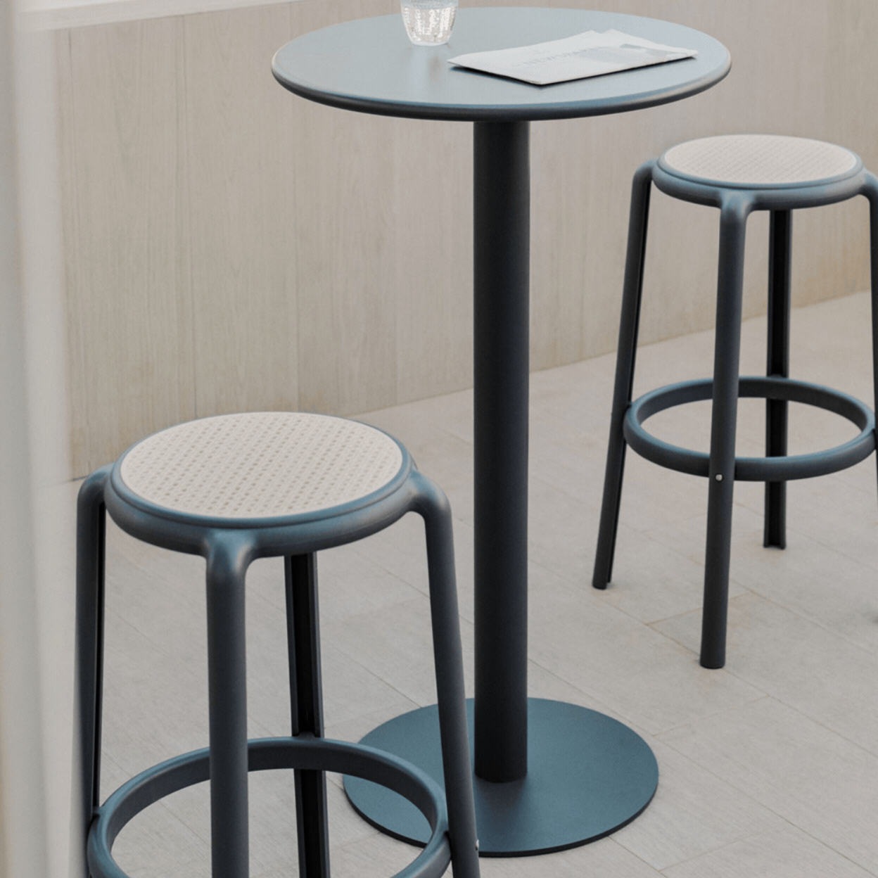 Round High Table Set &amp;Oslash;60 Cm in Mizzi Iron and 2 High Garden Stools in Omara Polypropylene in a rotating gif showcasing it in a naturally lit terrace and as a product against pale green background.