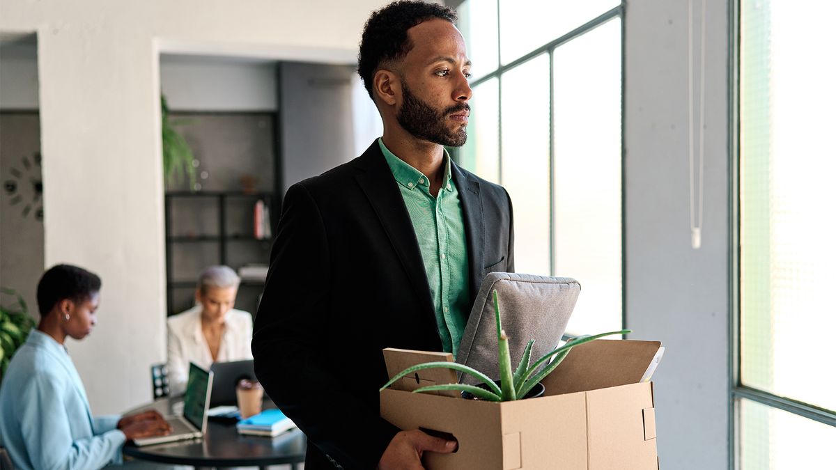 Businessman being fired in the office while other people continue working on the background.