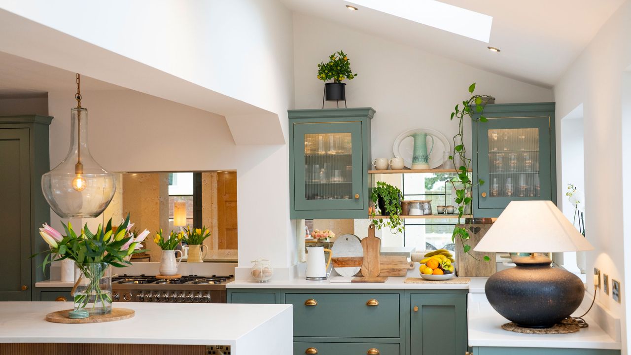 green Shaker kitchen with lamp on worktop and glass pendant lights