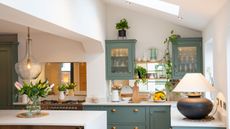 green Shaker kitchen with lamp on worktop and glass pendant lights