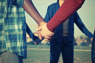 A group of young people holds hands.