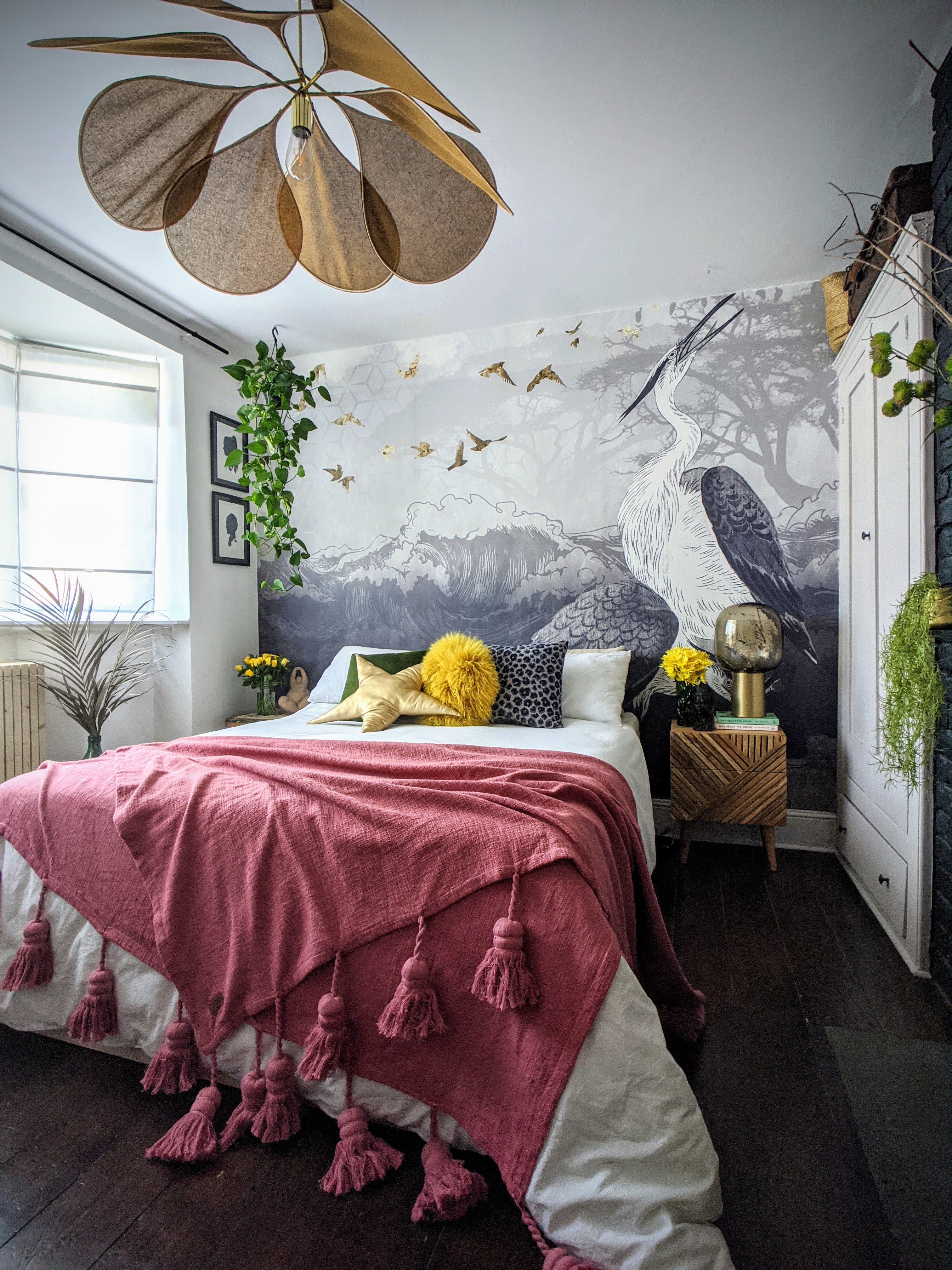 Crane bedroom mural frames bed with hot pink tassel throw and yellow detail