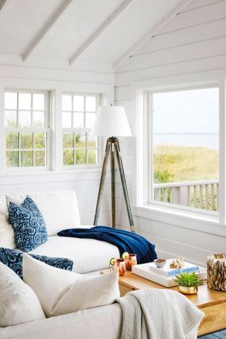 white sofas and chairs facing sea view across dunes from beach house with outside deck tripod standard lamp