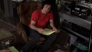 John Cusack in a red shirt writing on a yellow legal pad in High Fidelity