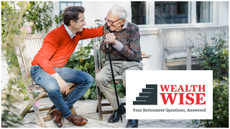 A man puts his elderly father on the back. His father is hunched over and holds a cane, but is smiling.