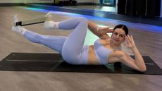 Woman on yoga mat uses resistance bands for strength training 