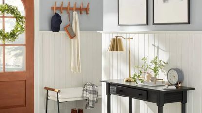 Neutral entryway with table, lamp, and wall hooks