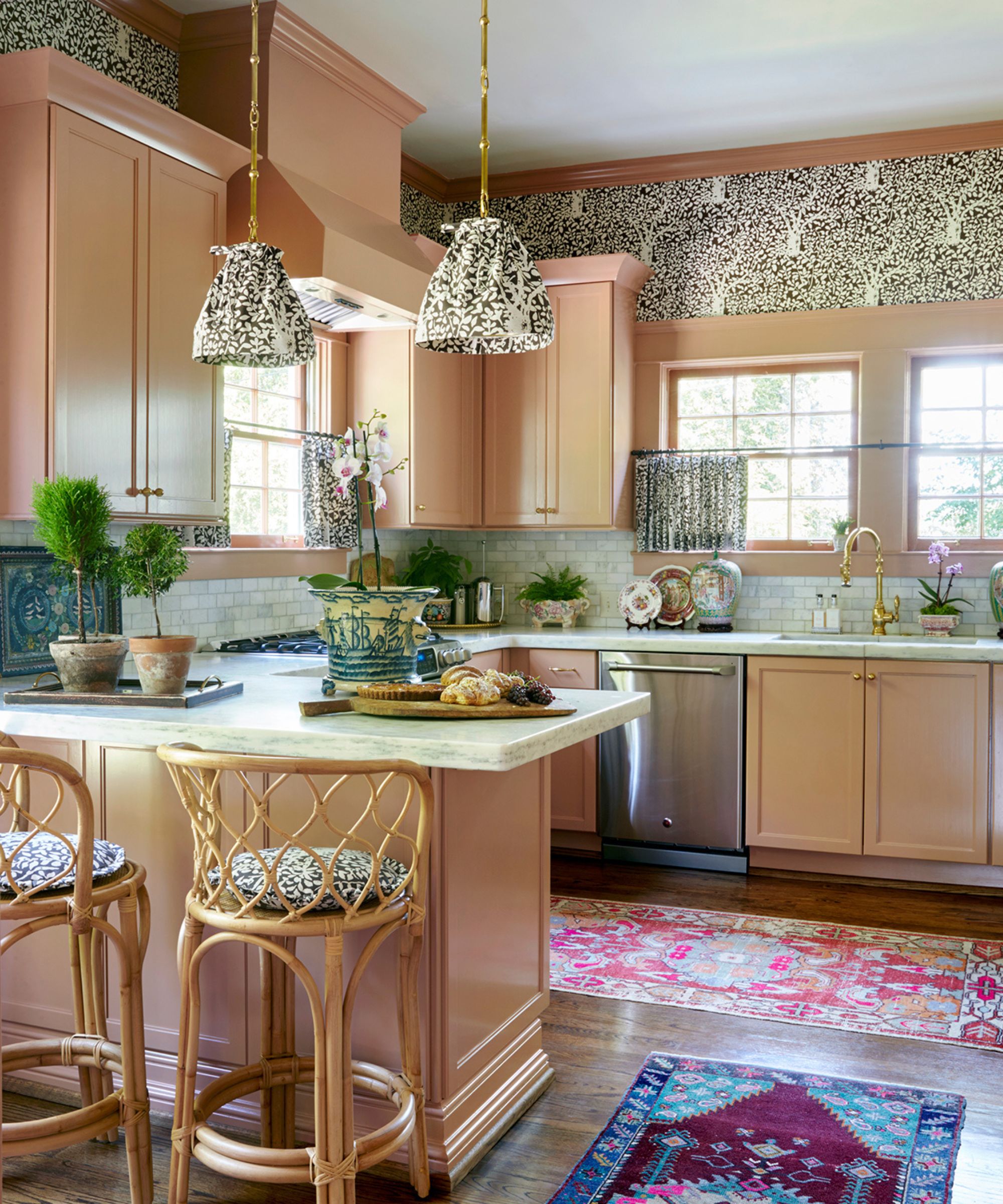 pink maximalist kitchen with two vintage runner rugs, fabric blinds, pendant lights, rattan bar stools with matching fabric cushions