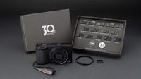 The Ricoh GR IV Anniversary Edition with its accessories on a gray background