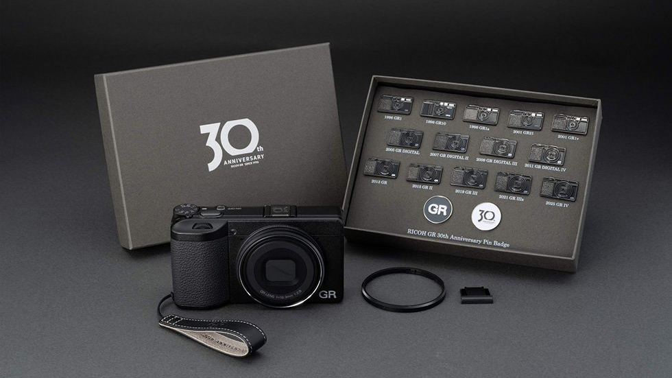 The Ricoh GR IV Anniversary Edition with its accessories on a gray background