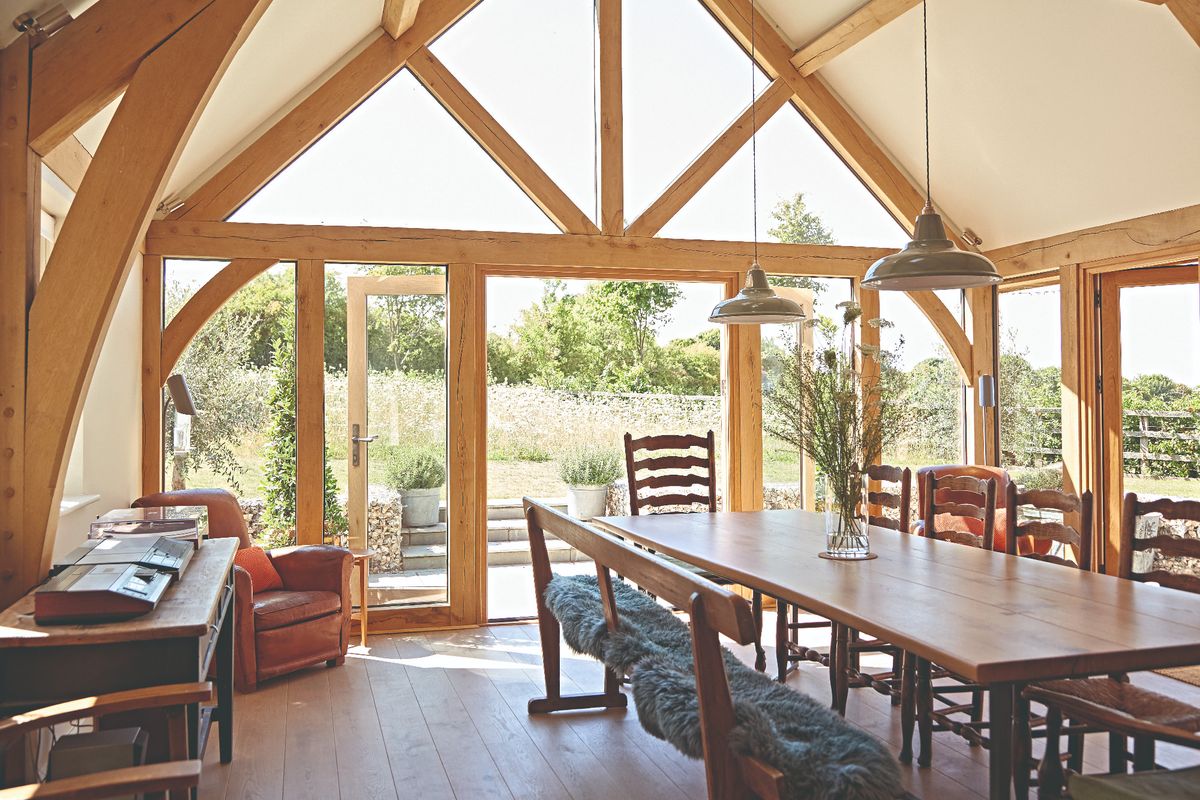 A dining room tables and chairs with two pendant lights suspended above inside an oak framed home