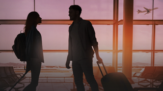 Silhouettes of a man and a woman with suitcases meeting at an airport, as a plane takes off in the background, for The Nevermets
