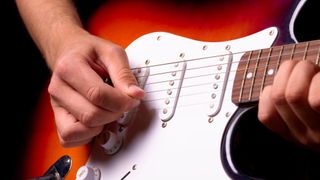 Close-up of picking hand on a Stratocaster-style electric guitar