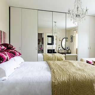 gold and white bedroom with mirrored wardrobes