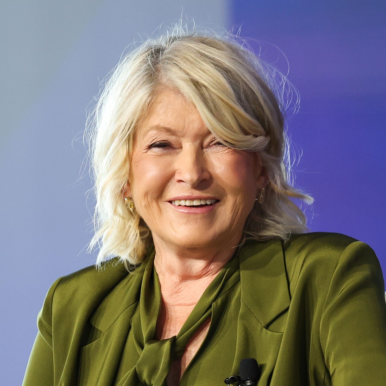 Martha Stewart in green against a blue background