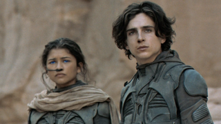 A still from the movie Dune in which , both wearing fremen suits and looking out into the distance