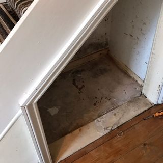 white cupboard below stairs and wooden flooring