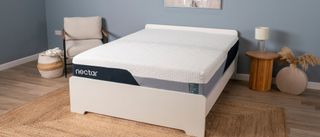 The image shows the Nectar Premier Memory Foam Mattress on a white bed frame against a blue bedroom wall