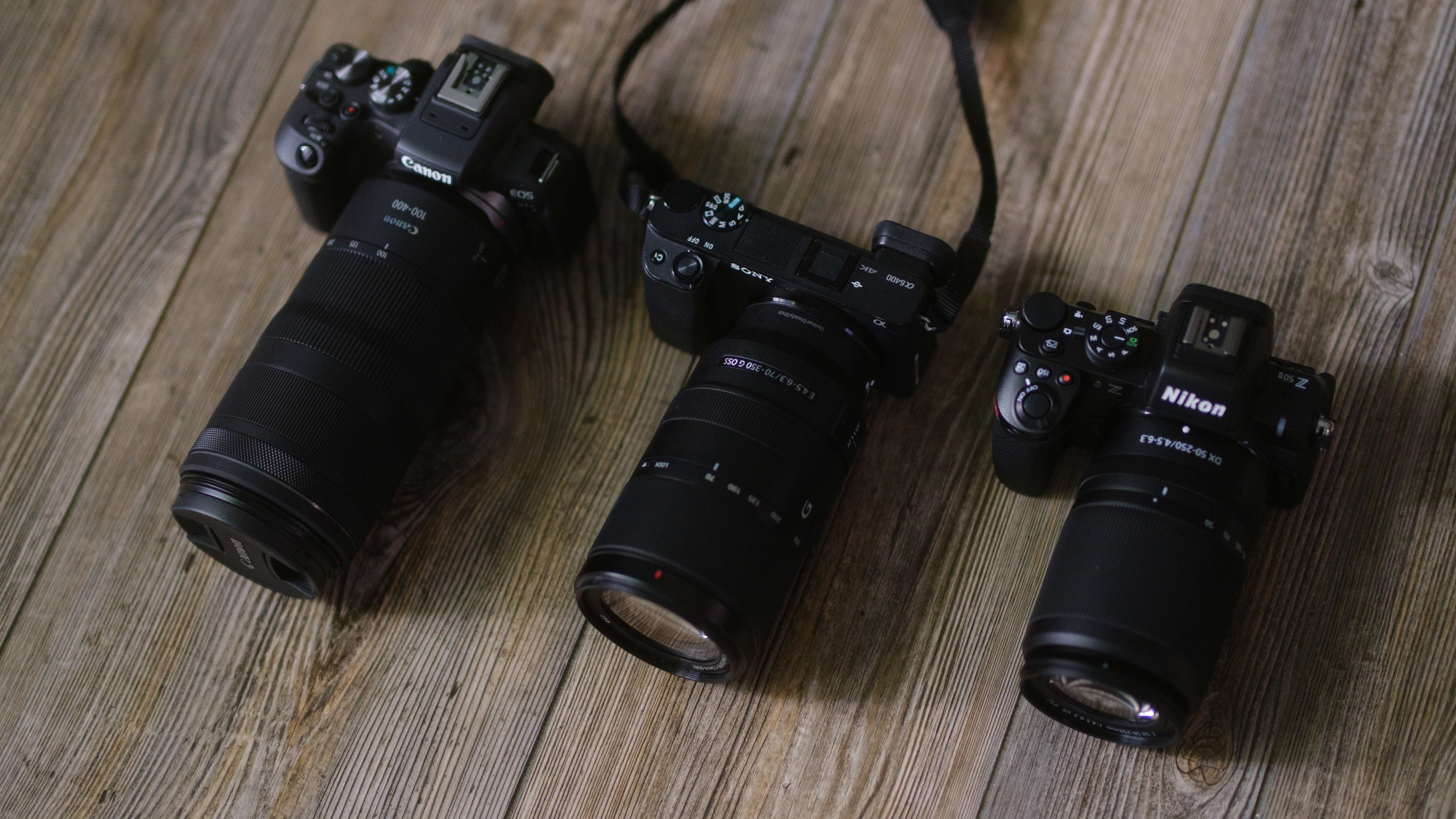 The Nikon Z50 II, Sony a6400 and Canon EOS R10 on a wood surface