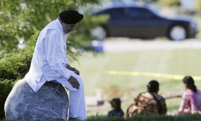 A man sits on a rock as police investigate a shooting at the Sikh Temple of Wisconsin in Oak Creek, Wis., that left six people, plus the gunman, dead on Sunday. Sikhism has long had roots in 