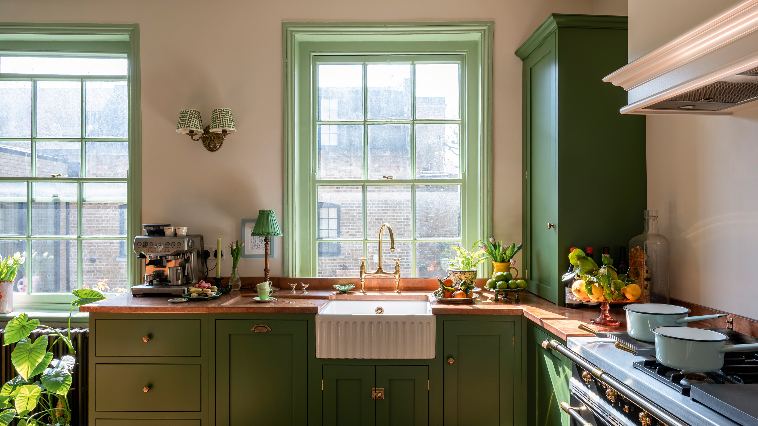 traditional kitchen with green cabinetry and woodwork, cream walls and wooden floors in a 17th-century london maisonette
