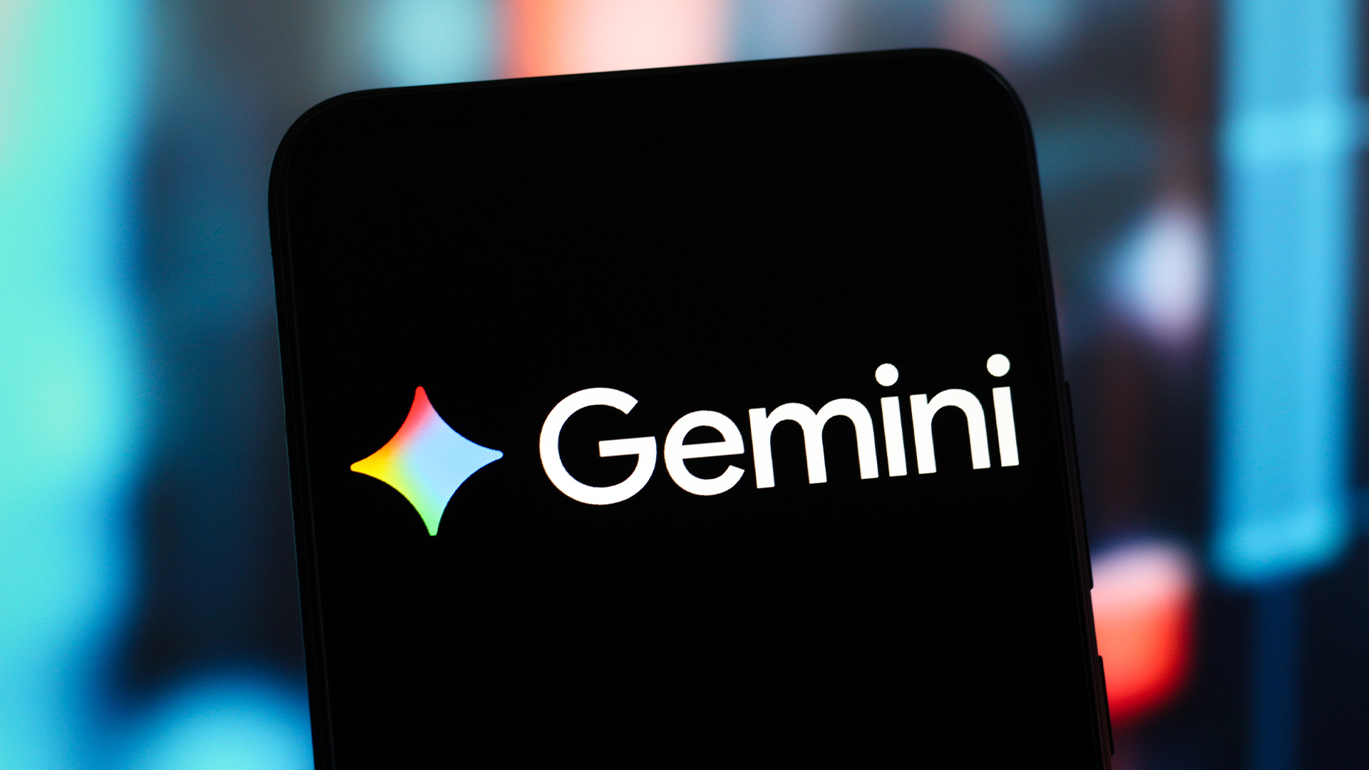 Google Gemini logo and branding pictured on a smartphone, with bar graph visuals blurred in background.