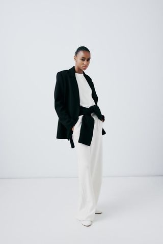 Zara model in white sweatpants and black blazer