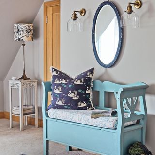 blue bench with cushion underneath round mirror