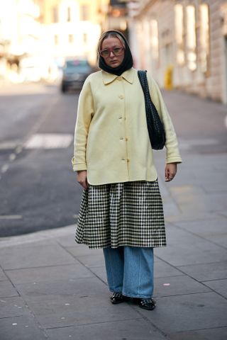 woman wearing jacket, dress, baggy jeans, and ballet flats