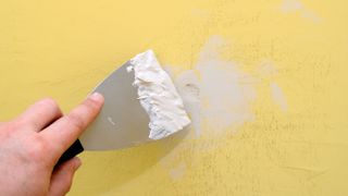 Filling cracks in wall with putty knife