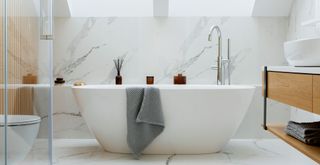 bathroom with white marble wall panels behind freestanding bath to show that tiles can be a bathroom design mistake