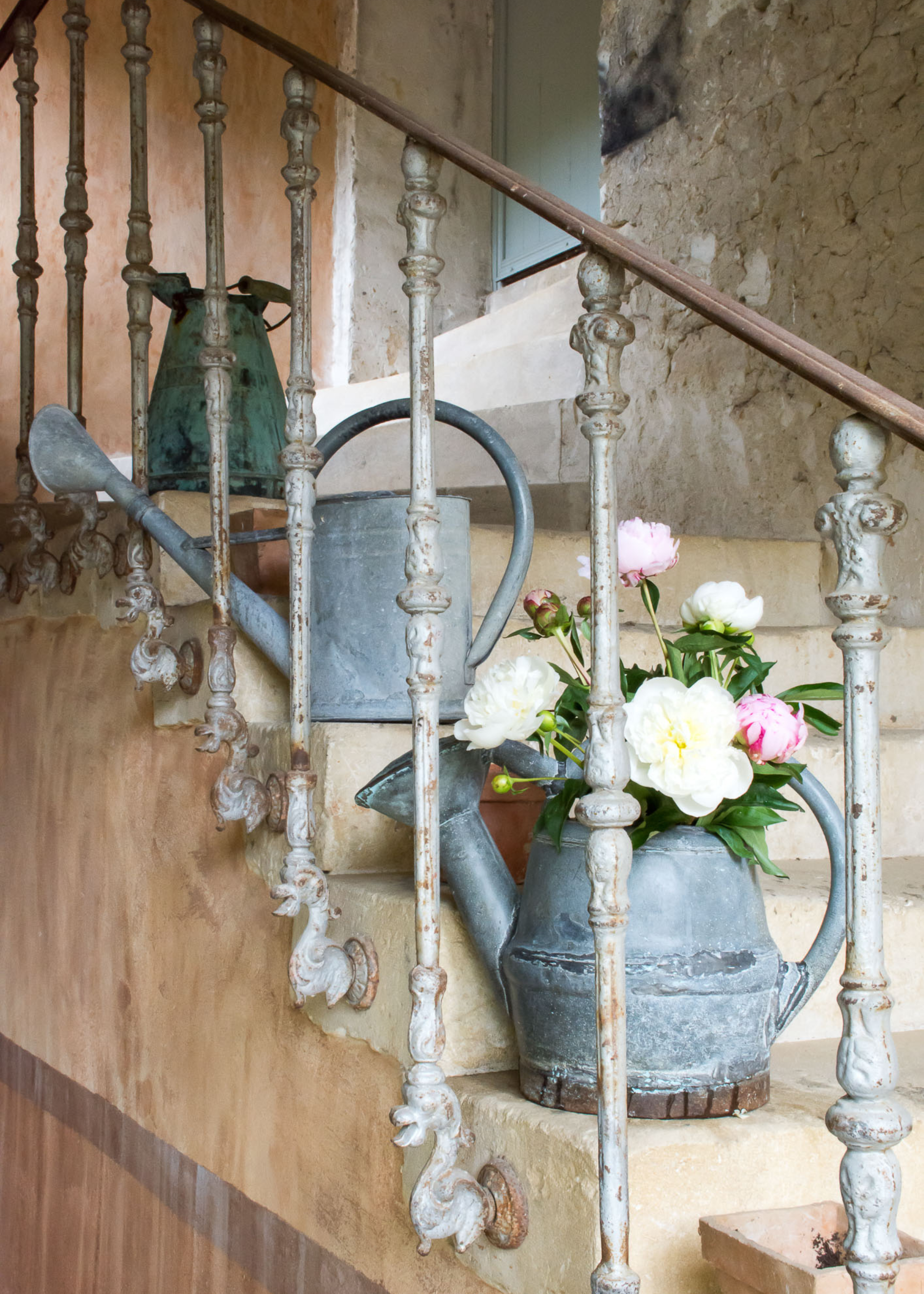An outdoor staircase with a trio of vintage watering cans with flowers