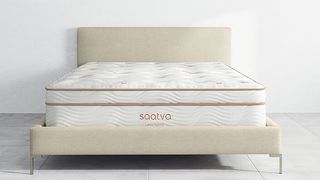 Saatva mattress sales, discounts and deals: The Saatva Latex Hybrid Mattress on a fabric bed frame with headboard