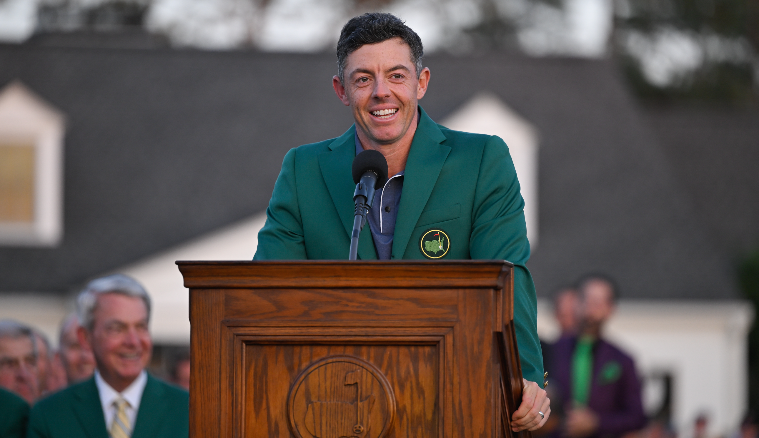 Rory McIlroy speaks at a stand wearing a Green Jacket