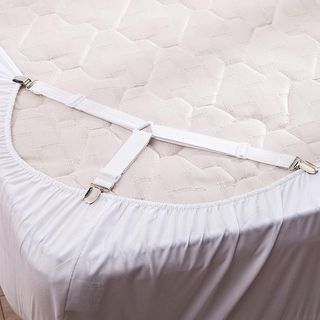 A white elasticated sheet strap holding a fitted sheet in place