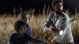The Abbott family creep through a field in A Quiet Place movie.