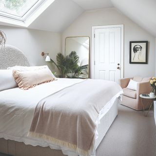 Neutral and pink bedroom with gold rimmed mirror, houseplant, armchair
